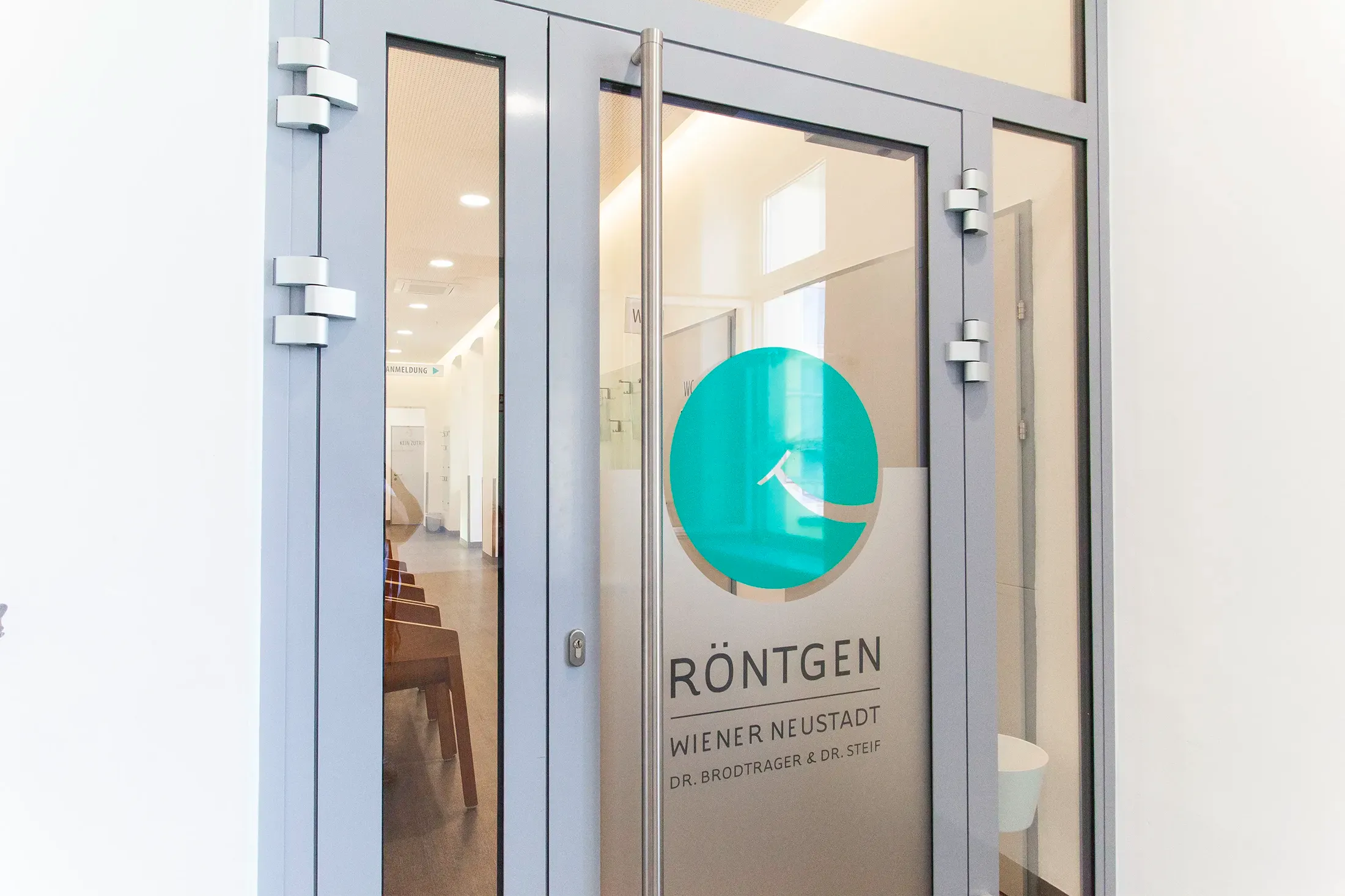 Eingangstür mit einem großen Logo auf der Glasscheibe in der Ordination Röntgen Wiener Neustadt